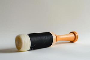 Wooden roller with black fabric and white felt for crafting on a neutral background photo