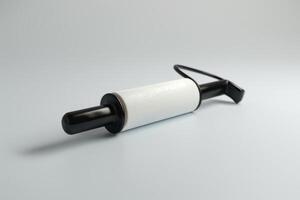 A lint roller with a black handle rests on a light gray surface, ready for cleaning fabric surfaces and removing pet hair photo