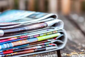 Stacked magazines on a wooden table in a cozy reading space during the afternoon photo