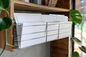 Organized mail storage with white envelopes on a wooden shelf in a bright, plant-filled interior photo