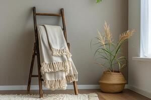 Cozy indoor corner with a knotted blanket on a wooden ladder beside a woven planter filled with greenery photo