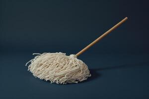 A simple mop resting on a dark background, showcasing its utilitarian design and soft cleaning fibers photo
