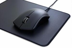 Black wired computer mouse resting on a smooth black mouse pad in a well-lit workspace photo