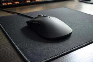 Black computer mouse resting on a sleek mouse pad in an office workspace during the day photo