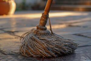 A close-up of a clean mop resting on a textured floor during the late afternoon sunlight photo