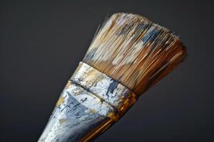 Close-up of a paintbrush with worn bristles, showcasing remnants of paint against a dark background photo