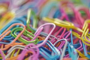 Colorful paperclips arranged in a chaotic pile on a desk during office hours photo