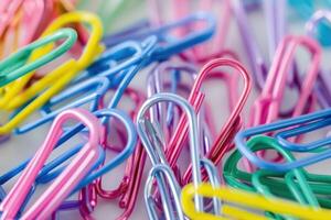 Colorful paper clips scattered on a desk surface in a creative workspace photo