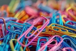 A vibrant assortment of colorful paperclips scattered on a desk surface photo