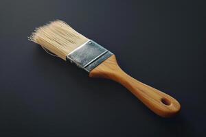A wooden handled paintbrush resting on a dark surface photo