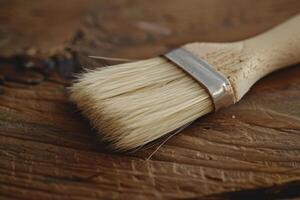 Close-up of a paintbrush resting on a wooden surface, showcasing its bristles and handle in natural lighting photo