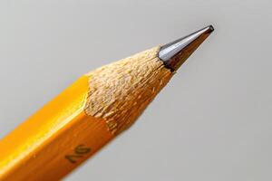 Close-up of a sharpened yellow pencil against a neutral background photo