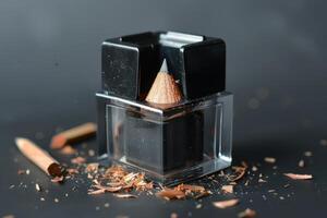 A pencil and sharpener with shavings on a black surface photo