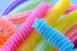 Colorful, textured pipe cleaners in vibrant hues arranged playfully on a light blue surface photo