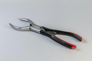 Close-up of a pair of sleek pliers with red rubber grips resting on a neutral background photo