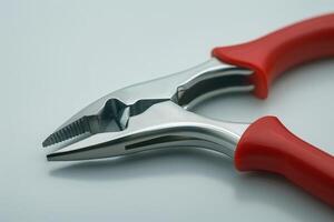 Close-up of red-handled pliers resting on a white surface photo