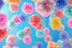 Colorful paper pom poms hanging against a blue backdrop for a festive celebration photo