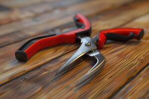 Sharp gardening shears with red handles resting on wooden table photo