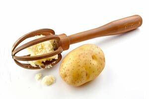 Mashed potato preparation with a wooden masher and a fresh potato on a bright background photo