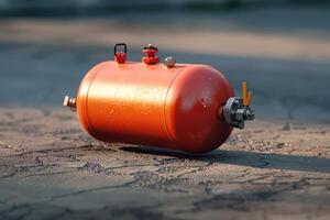 An orange gas cylinder lying on the ground in a sunny outdoor setting photo