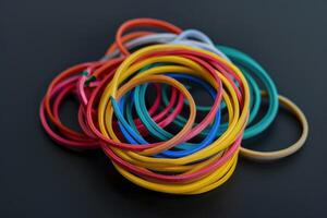 Colorful collection of rubber bands on a black surface, arranged in a tangled layout photo