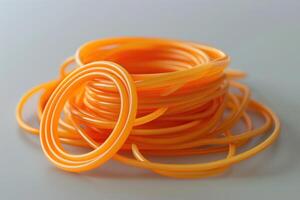 A pile of orange rubber bands on a white surface, with various sizes coiled and intertwined photo