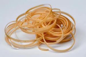 Rolled rubber bands scattered on a white surface, showcasing their flexible texture and varying sizes photo