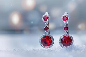 Elegant red gemstone earrings displayed on a snowy surface during wintertime photo