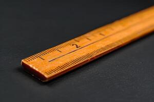 A close-up view of a wooden ruler showing measurements on a black background photo
