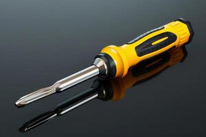 Close-up of a yellow and black screwdriver with a shiny metal tip resting on a reflective surface photo