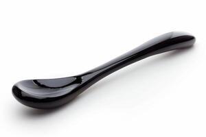 Elegant black ceramic spoon resting on a smooth surface, showcasing its sleek design and unique shape in bright light photo
