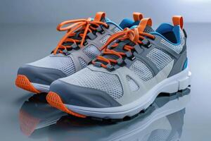 Modern athletic shoes on a reflective surface with orange laces and blue accents photo