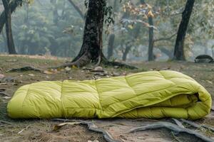 A bright green sleeping bag laid out on grass among trees in a serene forest during daylight photo