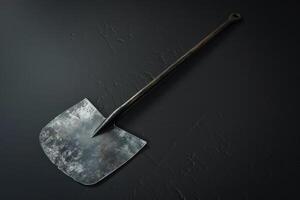 Rustic shovel resting on a textured dark surface photo