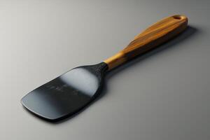 A wooden handle spatula resting on a smooth gray surface in natural light photo