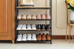 Organized shoe rack displaying various styles of footwear in a bright room with floral accents photo