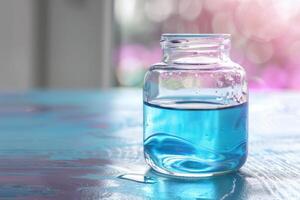 Clear glass jar filled with blue liquid on wooden table by bright window in a serene setting photo
