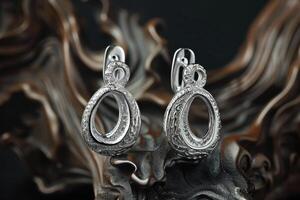 Elegant silver earrings with intricate design displayed on a textured dark background photo