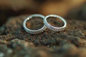 Close-up of two textured silver wedding rings resting on a rustic rock surface during sunset photo