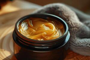 Golden cosmetic cream in a black jar with a soft towel in a warm setting photo