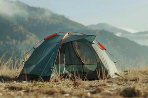 A camping tent set up in a grassy field against a backdrop of mountains during early morning light photo