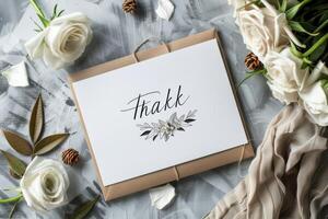 Thank you card with floral design surrounded by roses and pinecones on a textured gray surface photo