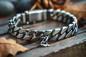 Close-up of a stylish metal bracelet on a wooden surface with dried leaves and polished stones in the background photo