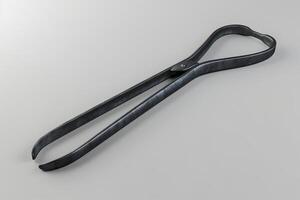 Metal tongs placed on a gray surface showcasing their sleek design and functional shape photo