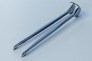 Stainless steel tongs resting on a smooth surface, reflecting light in a minimalistic setting photo