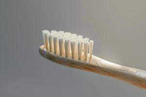 A close-up of a bamboo toothbrush with soft bristles against a neutral background photo