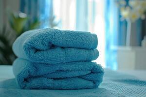 Soft blue towels neatly stacked on a bed in a bright, well-lit room during the afternoon photo