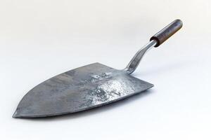 Metal garden trowel with a wooden handle resting on a light surface photo
