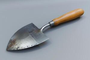 A weathered garden trowel rests on a gray surface, showcasing signs of wear from frequent use in gardening tasks photo