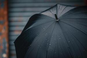 Black umbrella with raindrops standing against a weathered background on a rainy day photo